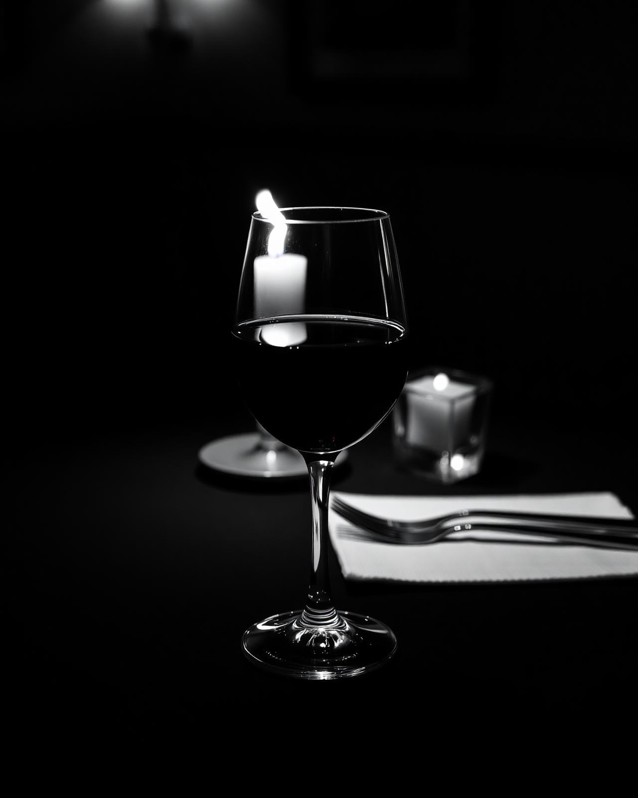 A glass of red wine on a dark dining table.